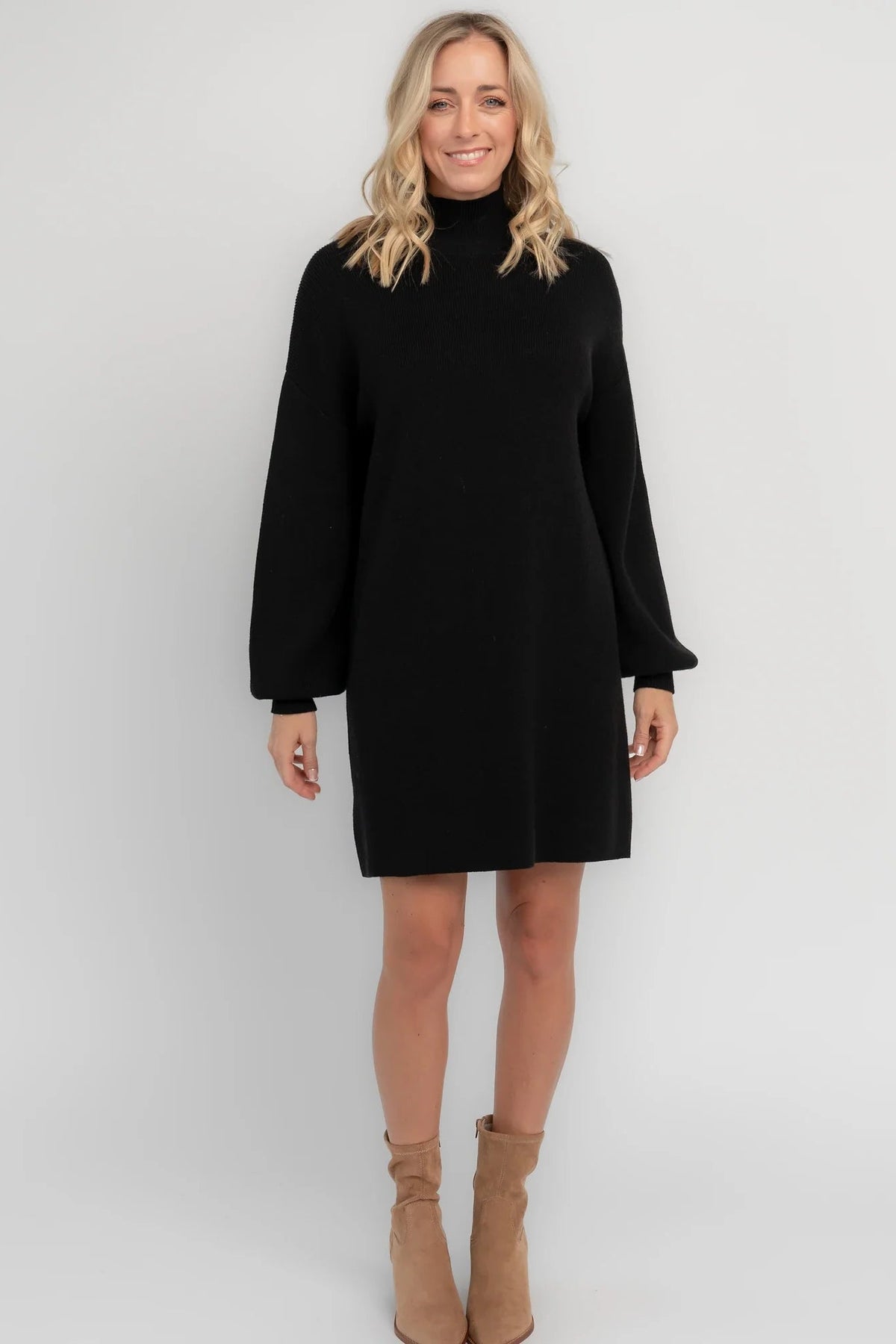 Black knit sweater dress with a mock neckline, long balloon sleeves, dropped shoulders, and a relaxed above-the-knee silhouette.